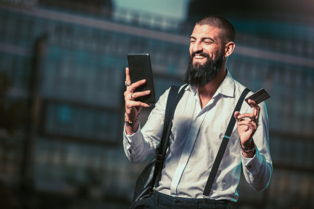 一名年轻的白人商人在户外手持平板电脑和信用卡图片下载