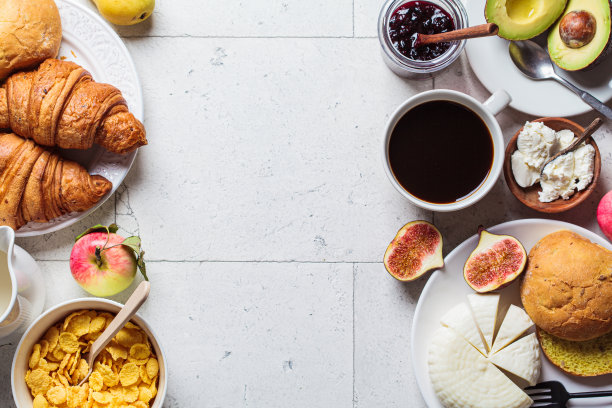 早餐桌上有玉米片，羊角面包，水果，奶酪和一杯咖啡。灰色瓷砖背景，俯视图。图片下载