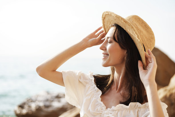 年轻快乐的黑发女人对着大海和岩石摆姿势图片下载