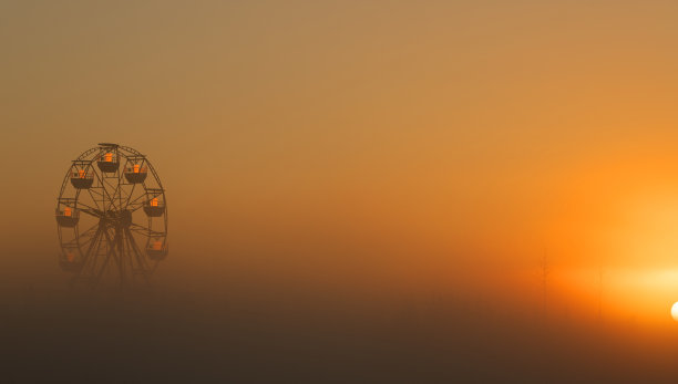 黎明时分雾蒙蒙的公园里的白色摩天轮。图片下载