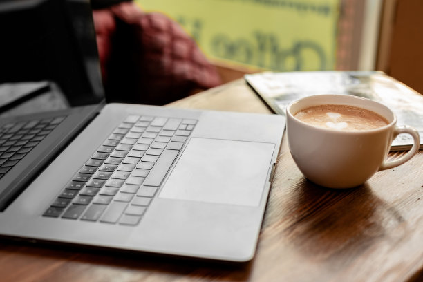 一杯卡布奇诺咖啡，灰色笔记本电脑放在木桌上。经营理念图片下载