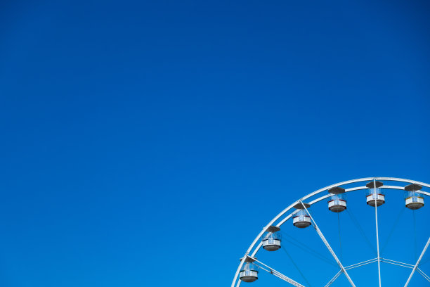 蓝色天空背景下的白色摩天轮。图片下载