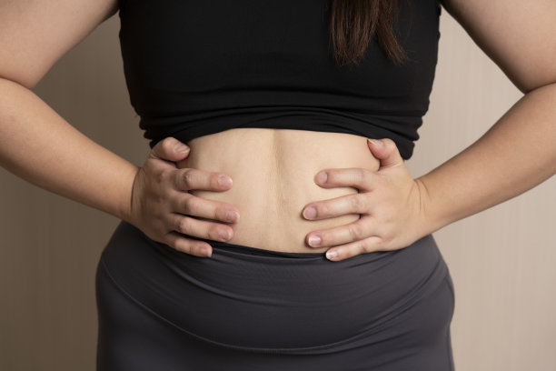 胖女人的手托着太多的腹部脂肪。腹部脂肪;胖乎乎的。饮食生活理念为女性减肥图片下载