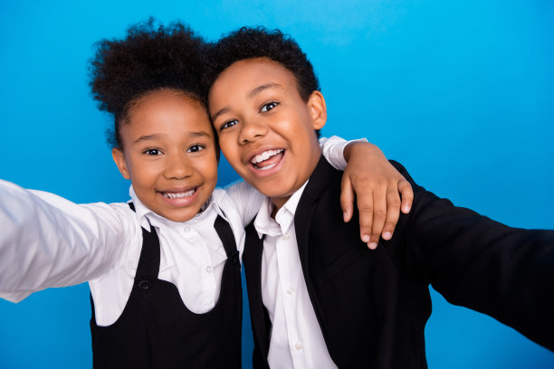 照片的小非洲裔美国孩子使自拍照穿制服微笑拥抱孤立在蓝色背景图片下载
