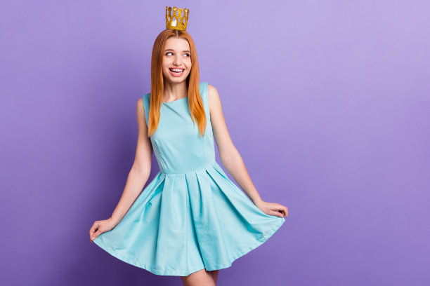 照片中的年轻迷人的女孩快乐积极的微笑戴着金色的皇冠公主孤立在紫色的背景图片下载