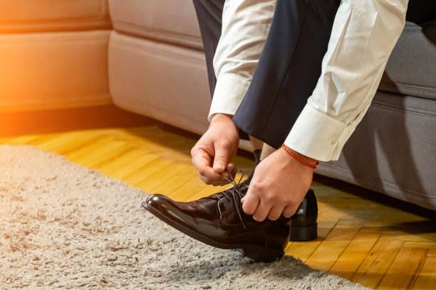 商人穿着古典优雅的鞋子。新郎在婚礼上穿的衣服，系好鞋带，准备婚礼图片下载