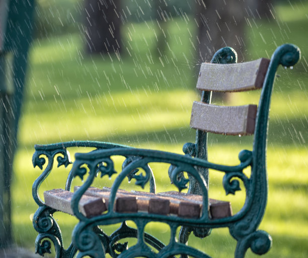 夏日公园里下雨时的绿色木凳。图片下载