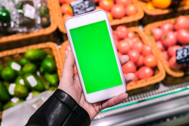 色度键。杂货店里一个女人拿着绿色屏幕的智能手机。购物中心。百货商店。购物中心。网上购物图片下载