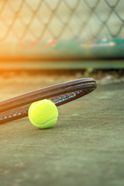 在阳光下的网球场上，网球和球拍合拢，运动背景与网球概念图片下载