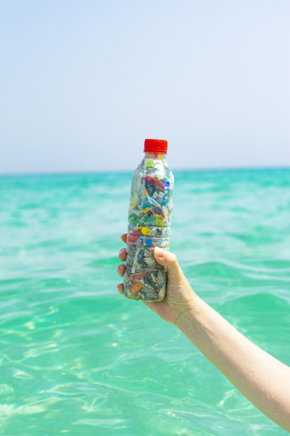 瓶子里装着从海里收集来的塑料微粒背景是大海。图片下载