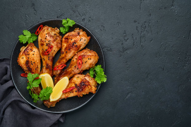烤鸡腿或鸡腿或烤烧烤配香料和番茄沙司在黑色盘子。顶部视图与复制空间。图片下载