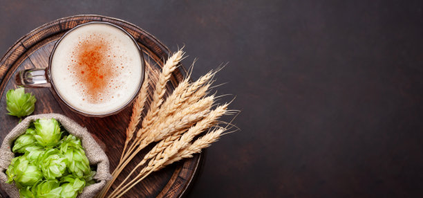 大啤酒杯，啤酒花和小麦在旧木桶图片下载