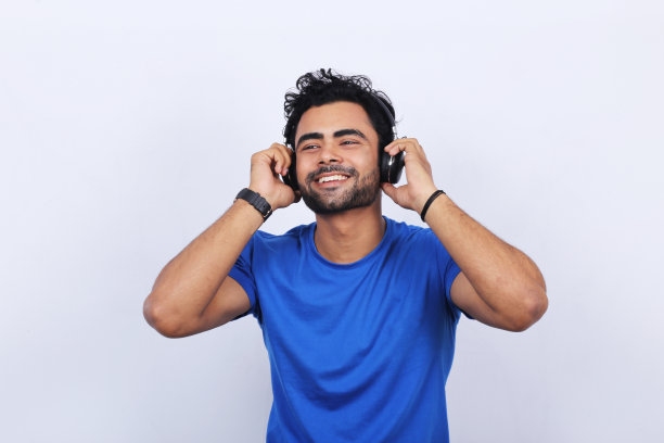 一名年轻的印度男子戴着无线耳机听音乐图片下载