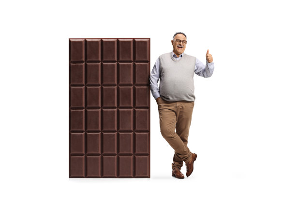 一位成熟男人倚靠在大型巧克力棒上，并竖起大拇指的全身像图片下载