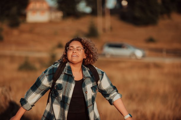 一位年轻的登山运动员在登山后坐在一块岩石上，用她的智能手机拍了张照片图片下载