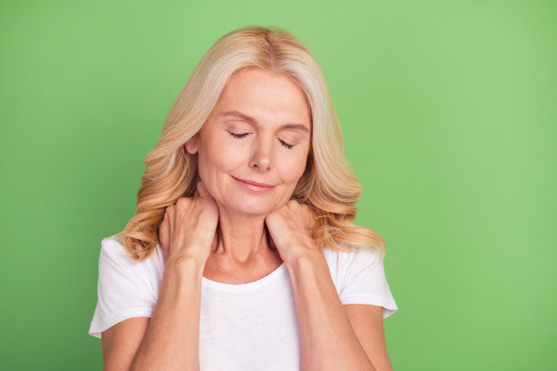 照片肖像老年妇女触摸颈部需要按摩孤立在柔和的绿色背景图片下载