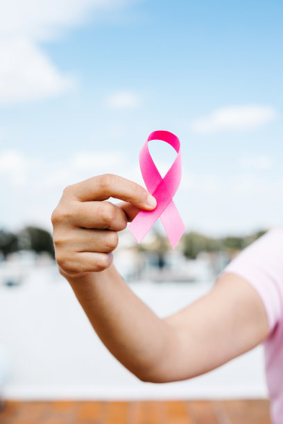 拉丁美洲的一位妇女手拿蓝色背景的粉红色乳腺癌意识丝带图片下载