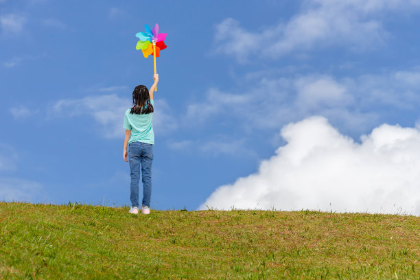 亚洲小女孩带着风车，夏日小女孩手握风车，快乐的孩子在户外玩耍图片下载