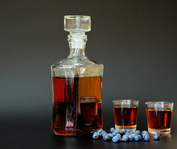 自制野莓利口酒，一瓶两杯，黑色背景，旁边是一堆成熟的蓝莓。图片下载