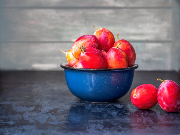 蓝色杯子里装着熟透的红李子，当点心吃图片下载
