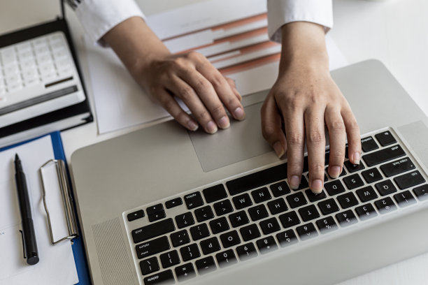 特写照片的女人在西装在笔记本电脑键盘上打字，商业妇女打字聊天的商业伙伴通过在线信使。在通信中使用技术的概念。图片下载