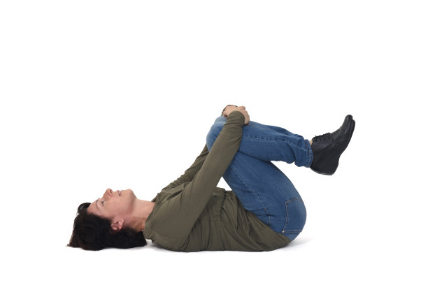 沉思的女人躺在地板上，双膝着地，看着白色的背景图片下载