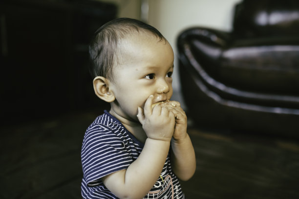 小男孩坐在地板上，脸上堆满了食物，面带微笑图片下载