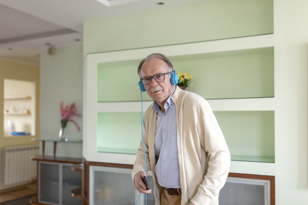 一张欢快的爷爷在家里戴着耳机跳舞的照片。图片下载
