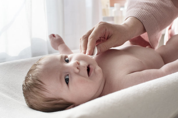 妈妈用棉垫为刚出生的孩子擦脸。早上babycare例行公事。医药，保健，童真，儿科，婴儿概念图片下载