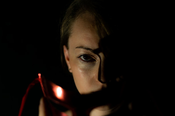 一名年轻女子暗而神秘的低调肖像，灯光效果，玩光，烛光，面具，大头照和特写。图片下载
