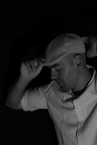 一个年轻人的肖像，戴着眼镜和帽子，在黑暗的房间在黑色的背景。图片下载