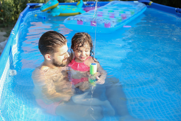 爸爸和女儿在游泳池里玩耍和拥抱。库存图片图片下载