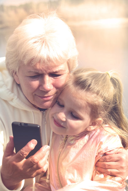 奶奶和可爱的孙女一起玩手机，奶奶和小女孩玩手机自拍图片下载