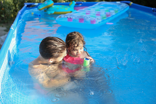 爸爸和女儿在游泳池里玩耍和拥抱。库存图片图片下载