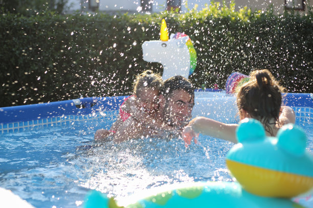 父亲和孩子们在游泳池里玩。库存图片图片下载