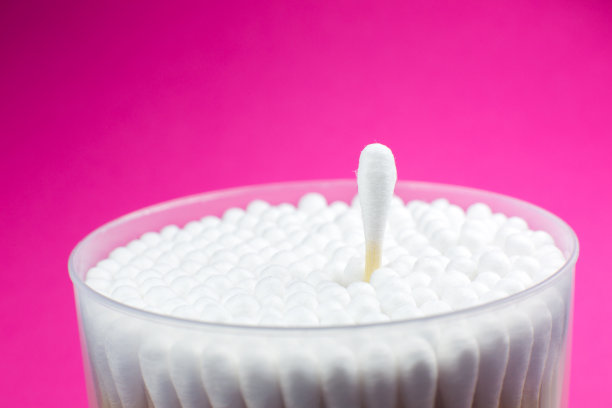 耳棉拭子上的粉红色背景。卫生的耳朵。图片下载