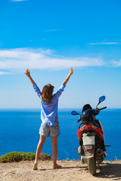 女人骑着摩托车望着远方的地平线。图片下载