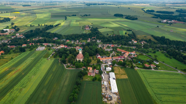 在一个晴朗的多云的日子，用无人机拍摄了一个典型的波兰山区城镇的住宅区和农民的田地。图片下载