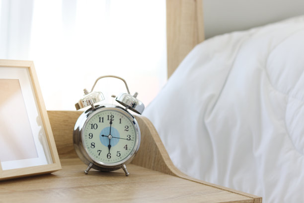 早上六点，白色卧室的木桌上放着闹钟。图片下载