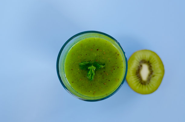 俯视图新鲜美味的绿色冰沙在一个由奇异果，奇异籽制成的玻璃杯。创意健康排毒饮料概念，饮食或素食概念。本空间图片下载