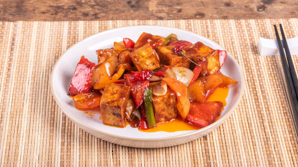 用筷子夹着洋葱和辣椒的酸甜豆腐上桌，特写镜头图片下载