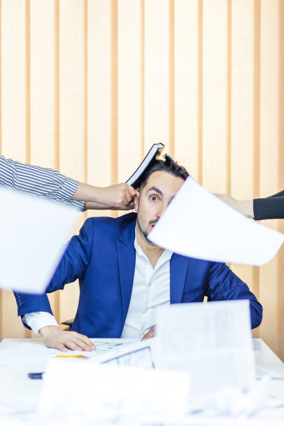 一个穿着蓝色西装的商人坐在办公室里有很多工作要做。图片下载