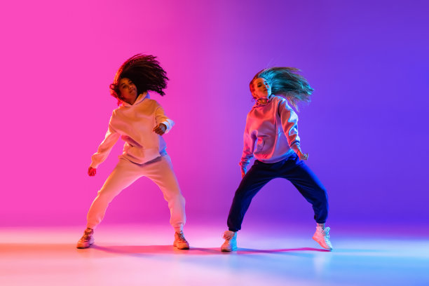 两个美丽的活跃的女孩跳舞梯度粉红紫色霓虹灯工作室背景图片下载