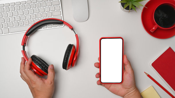 男子手持耳机，在白色的桌子上使用智能手机。图片下载