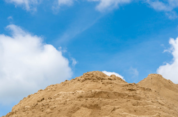 粗糙的沙堆，晴朗的天空。图片下载
