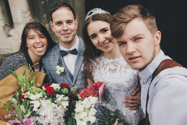 在神圣的婚礼后，时尚快乐的新娘和新郎在教堂的背景下微笑着与家人自拍。美丽动人的婚礼新人与宾客自拍图片下载