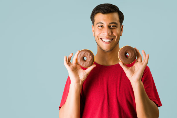 有魅力的男人兴奋地吃甜甜圈图片下载