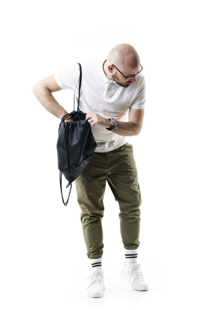 困惑的年轻秃头剃了胡子的书呆子寻找包寻找遗忘或丢失的东西。图片下载