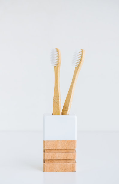 用天然材料制作的木制杯子中的竹牙刷，与白色背景隔离图片下载