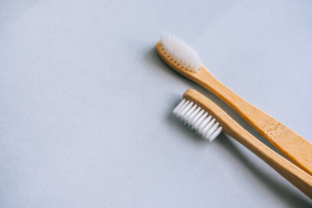 用天然材料制作的竹制牙刷，在灰色背景上孤立，特写。图片下载